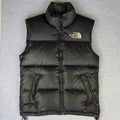 Black puffer vest with The North Face logo on a gray background