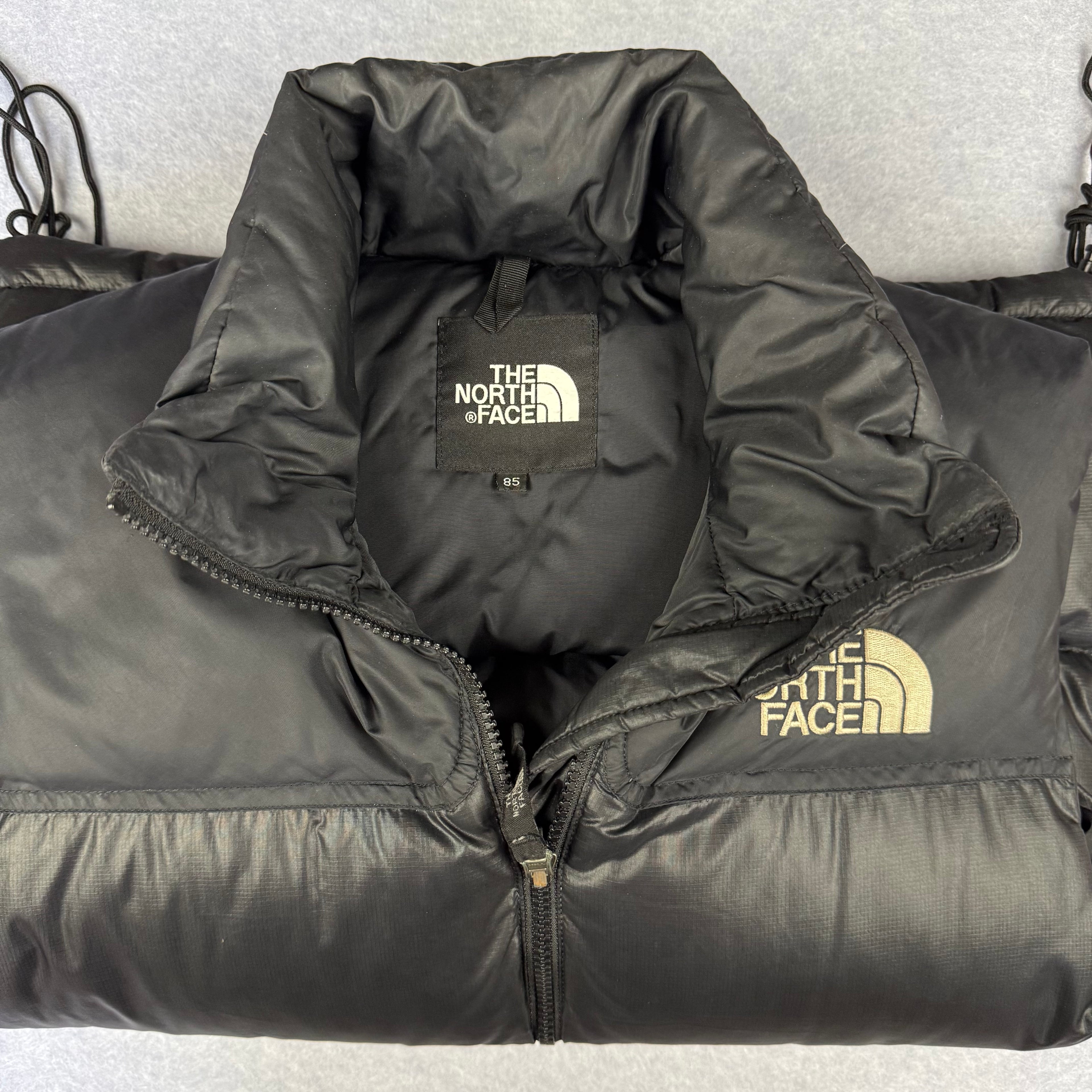Black North Face puffer jacket on a light gray background