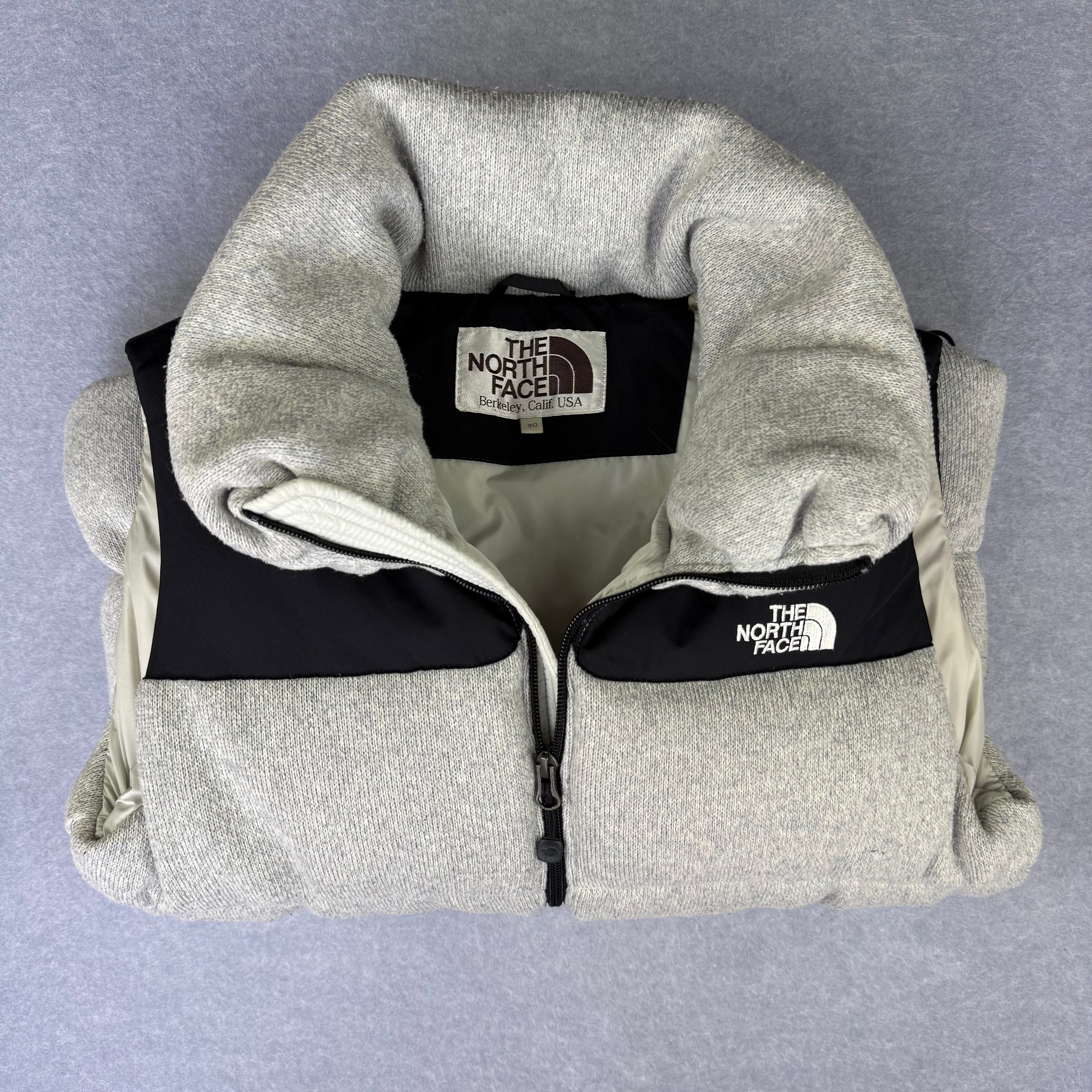 Gray fleece jacket with The North Face logo on a gray background