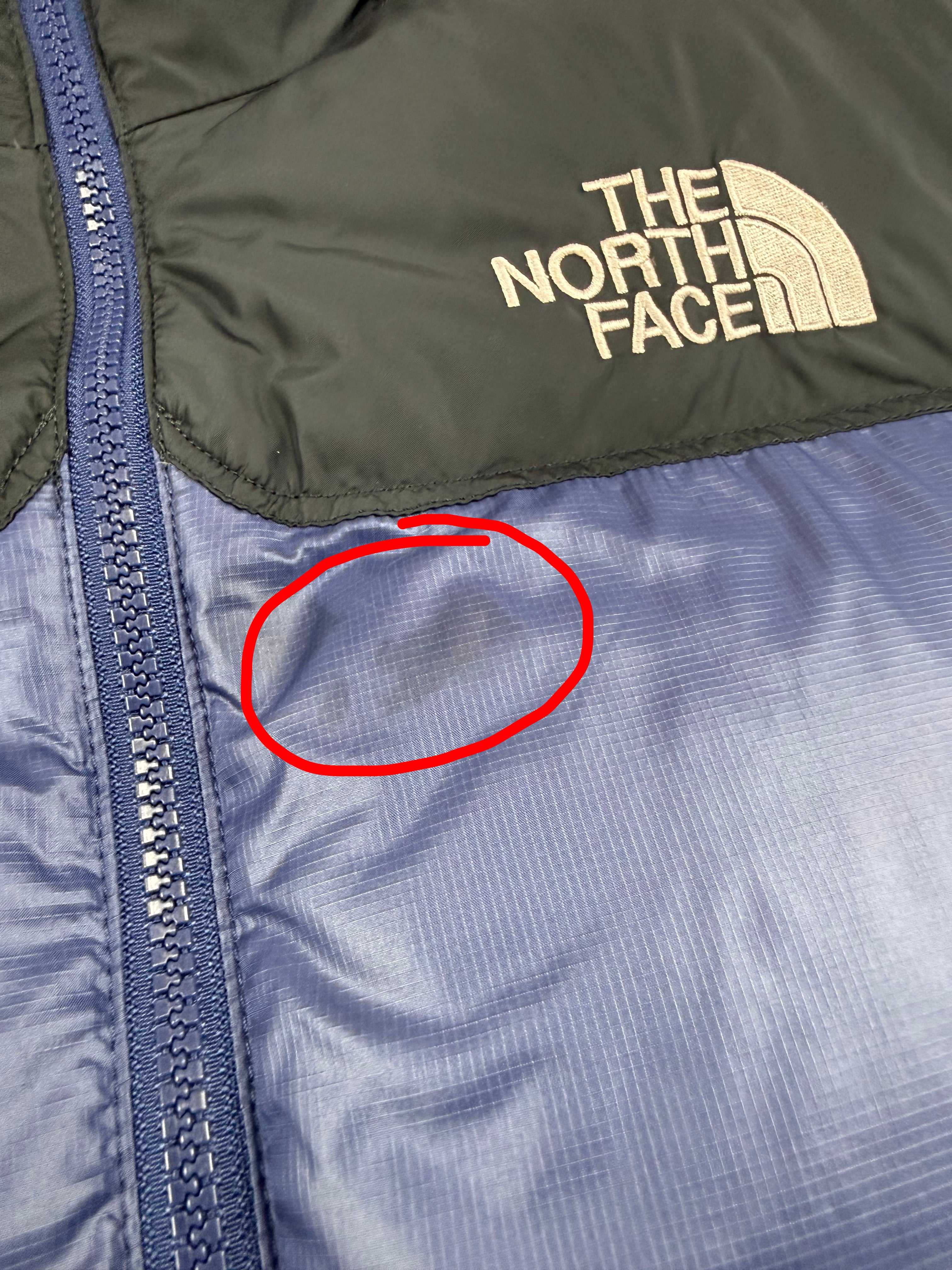 Close-up of The North Face logo on a jacket with blue and black colors.