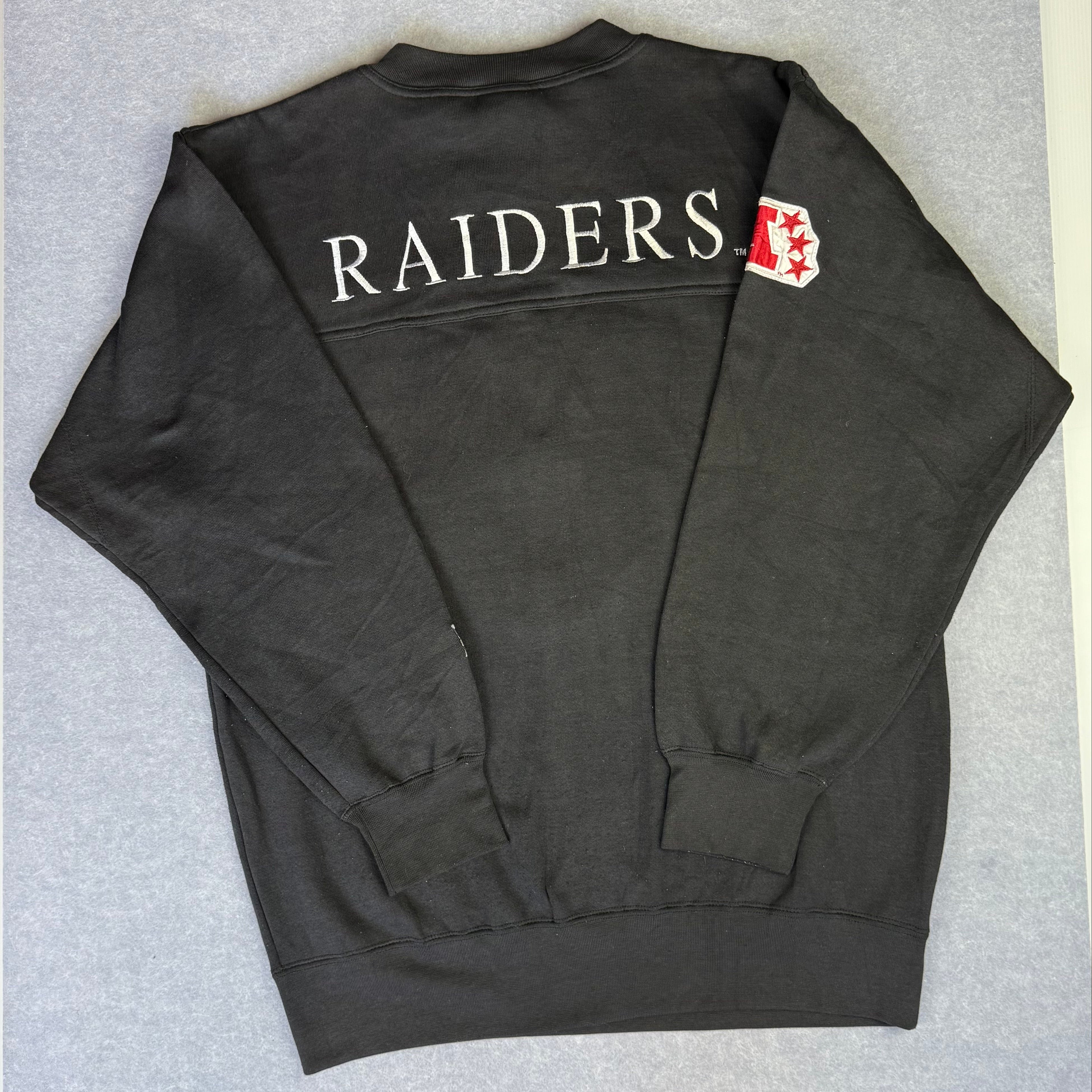 Black sweatshirt with 'RAIDERS' text on a gray surface